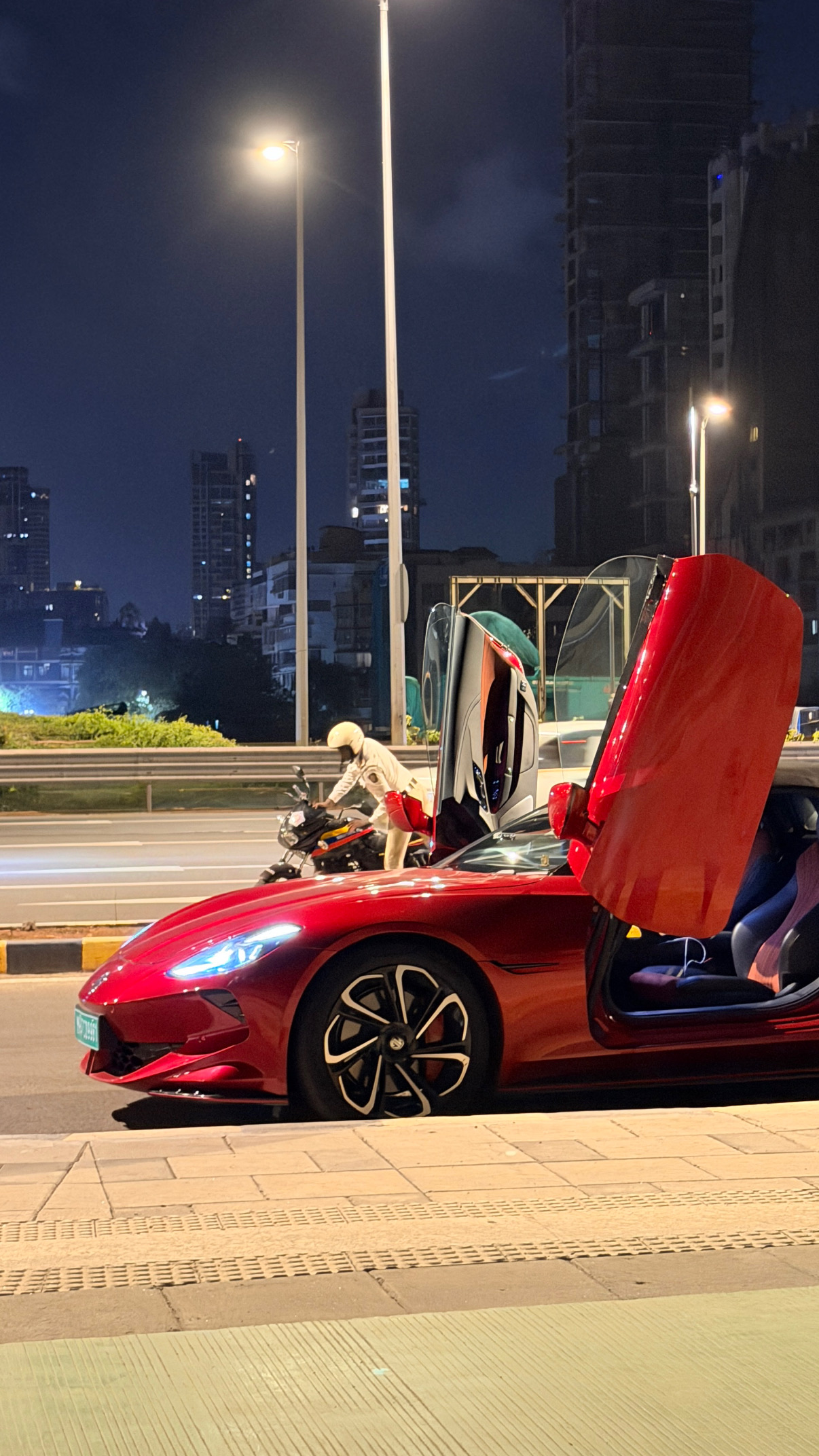 Red sports car with raised doors on a city street at night